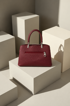 Gia Sling back view in burgundy with exterior zipper pocket, textured PU leather and silver-tone hardware on a minimalist studio pedestal