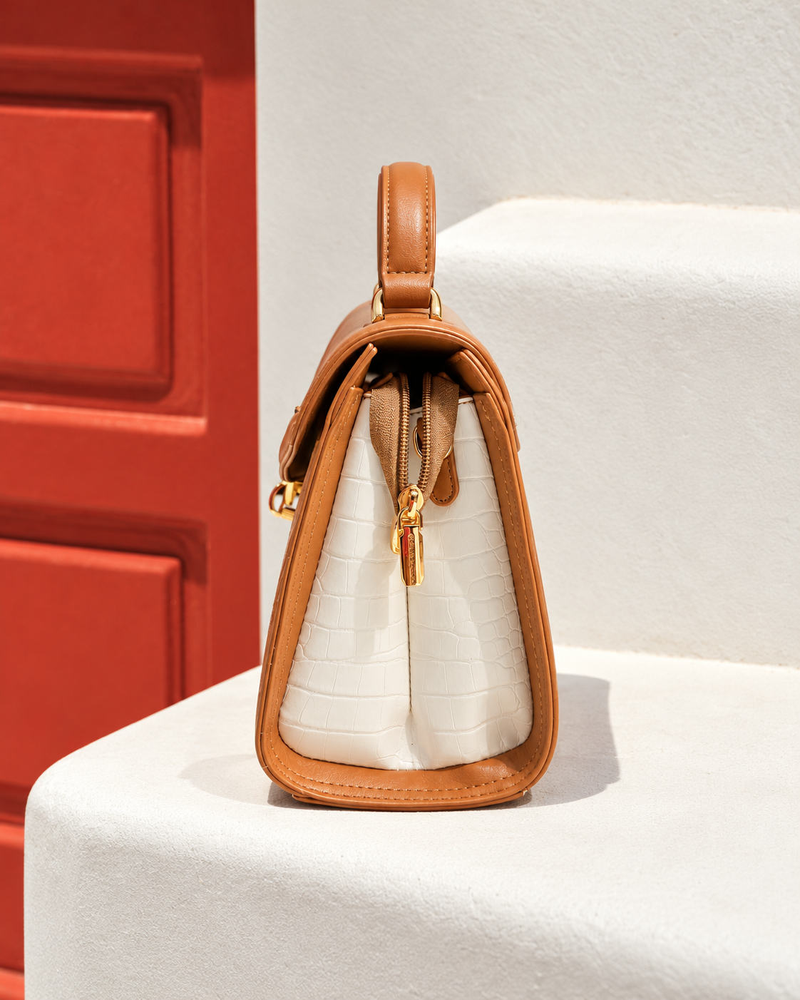 Bela Sling side profile in caramel brown with ivory crocodile-textured panel, structured design and gold-tone zipper hardware