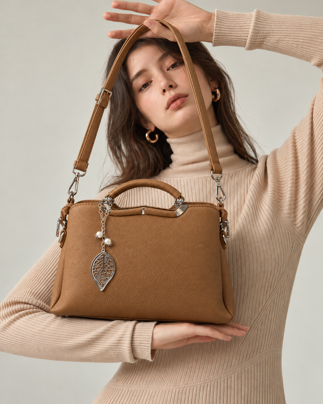 Gia Sling beige lifestyle view with female model, textured PU leather, detachable shoulder strap, silver-tone leaf charm and pearl accents